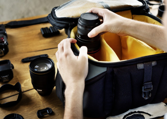 Person packing a camera bag with several lenses