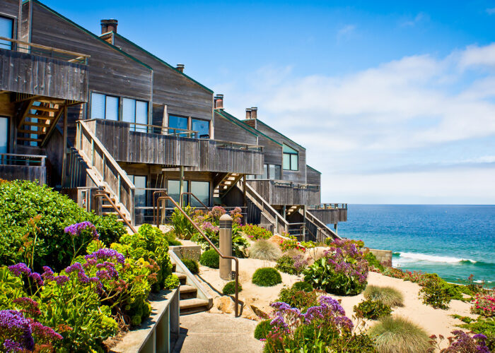 A row of oceanfront townhomes adjacent to a landscaped sand dune.